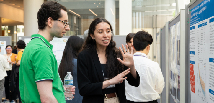 A trainee shows a viewer the details of their poster