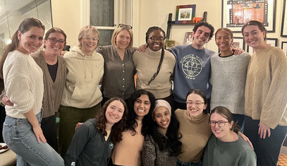 A group of current residents under a pink neon sign.