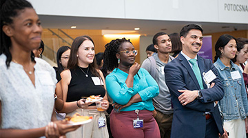 A crowd of people from Feinberg at the diversity reception listen to a presenter.