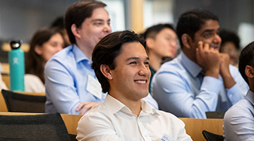 Someone at an event smiles in the seat of an auditorium.