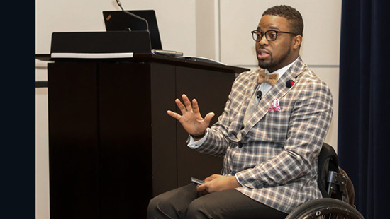 Dr. Oluwaferanmi Okanlami, sitting in a wheel chair, speaks as part of the Lyceum series.