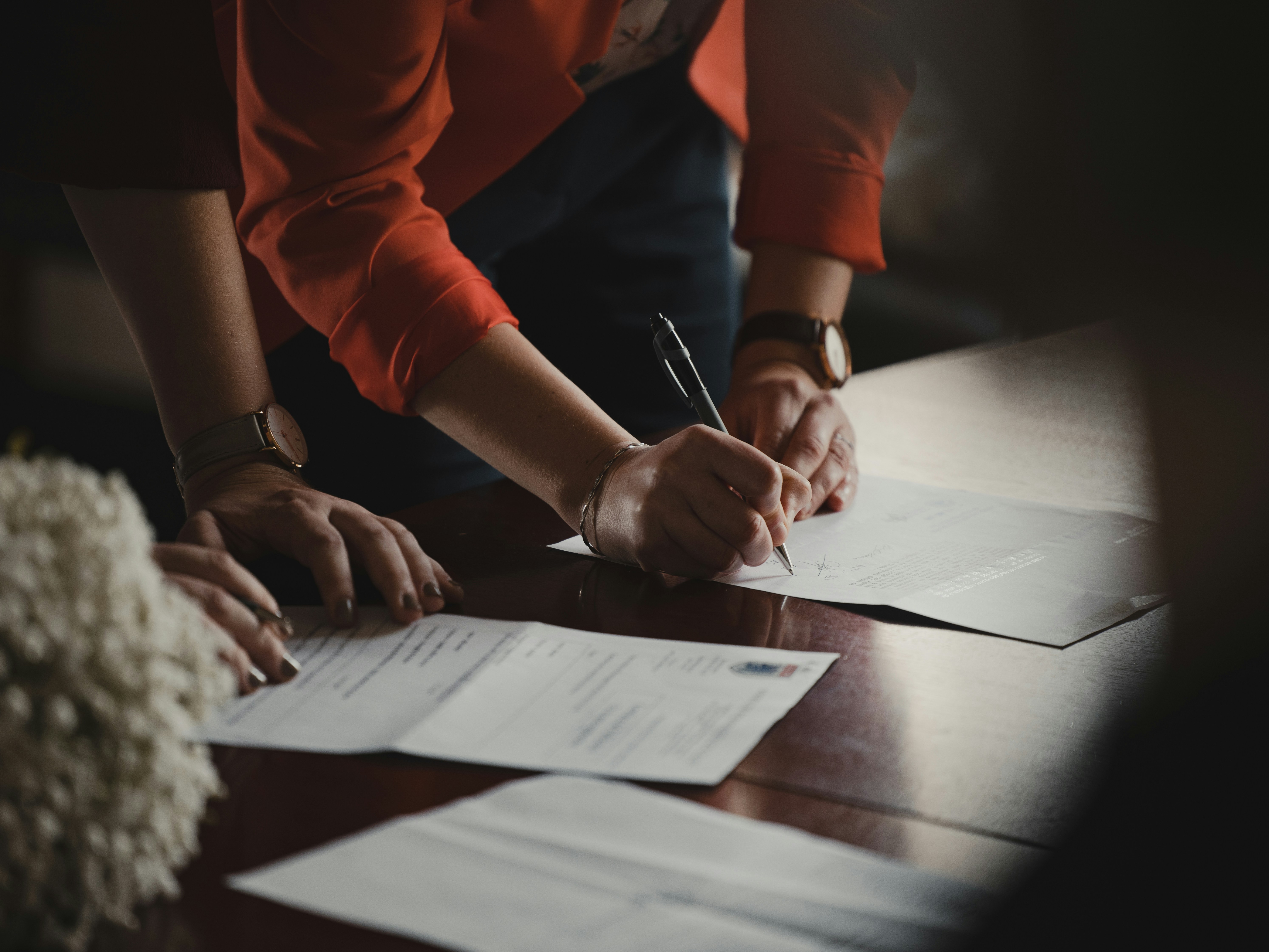 image of a person signing a document on a table