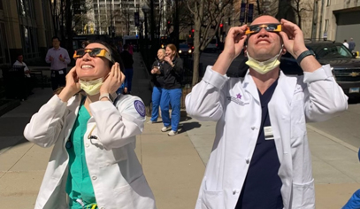 Two residents looking at the solar eclipse with eclipse glasses on.