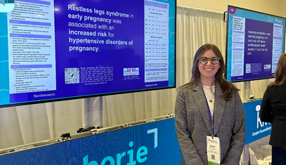 A resident posing in front of her research poster