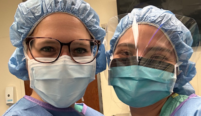 Two residents in surgical garments posing for a photo